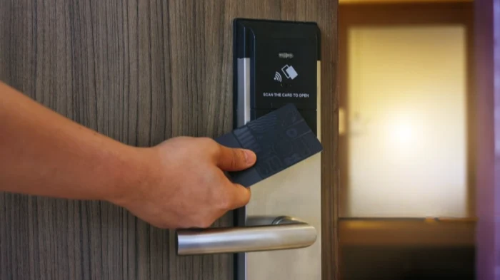 Hand using a hotel key card to unlock a door, illustrating the convenience and security of modern hospitality access solutions.