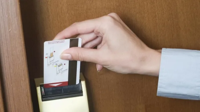 Hand using a magnetic stripe card to unlock a door, demonstrating the reliability and ease of use of Smart Innovation's card technology.