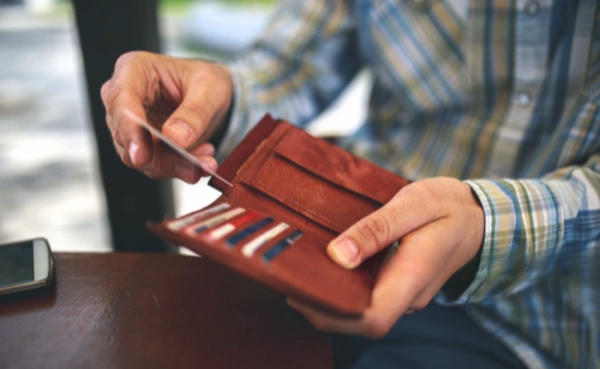 Person placing a hotel key card into a wallet, addressing the common concern about deactivation when near cell phones or credit cards.