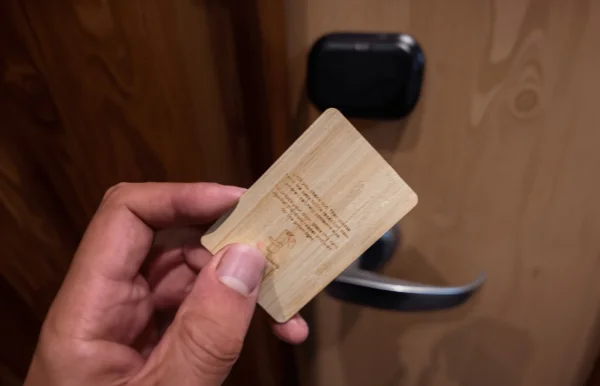 Hand holding a hotel key card made of wood, illustrating Smart Innovation's commitment to eco-friendly and sustainable hospitality solutions.